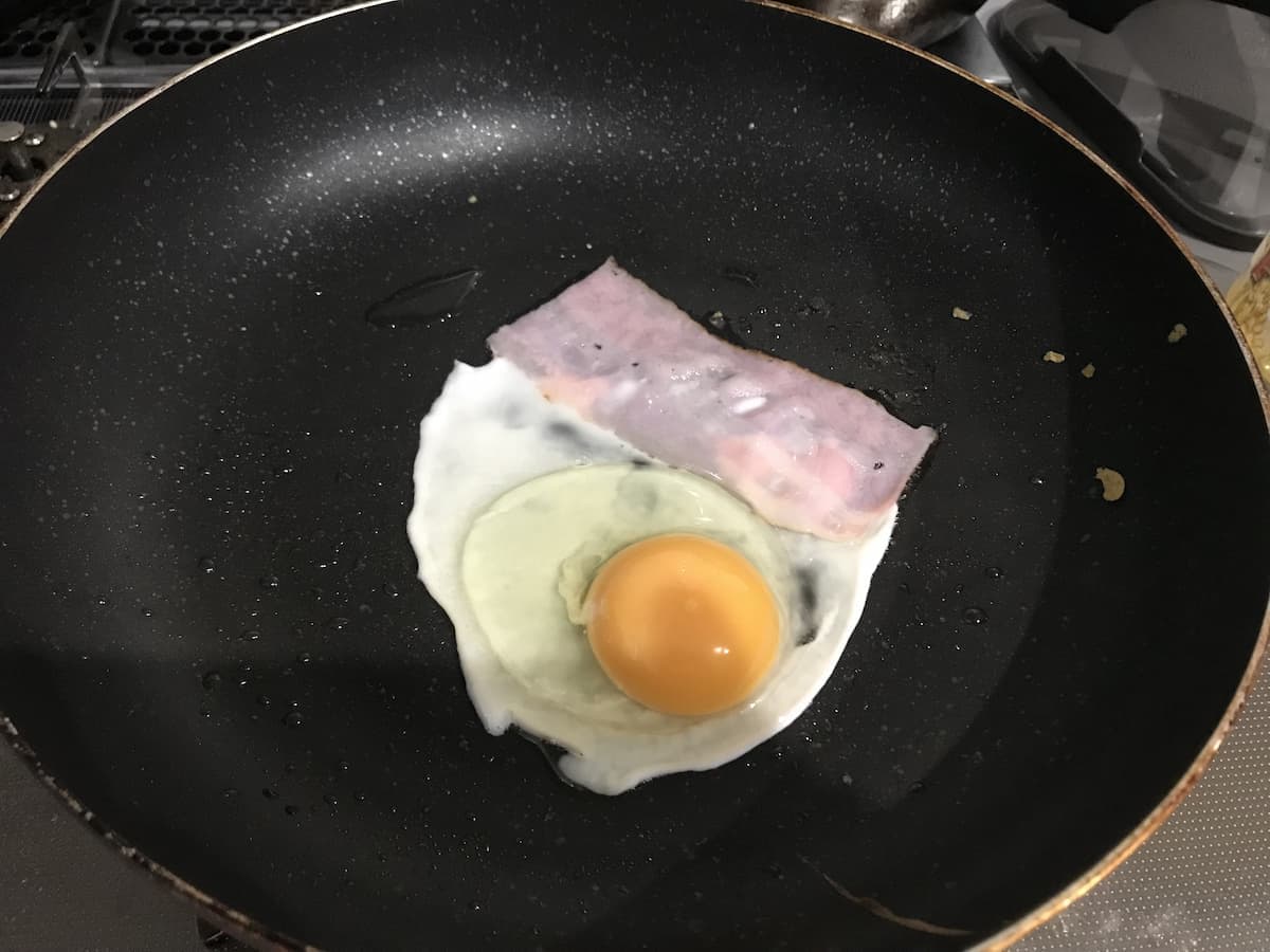 チーズベーコンエッグ　卵を焼いてる写真」